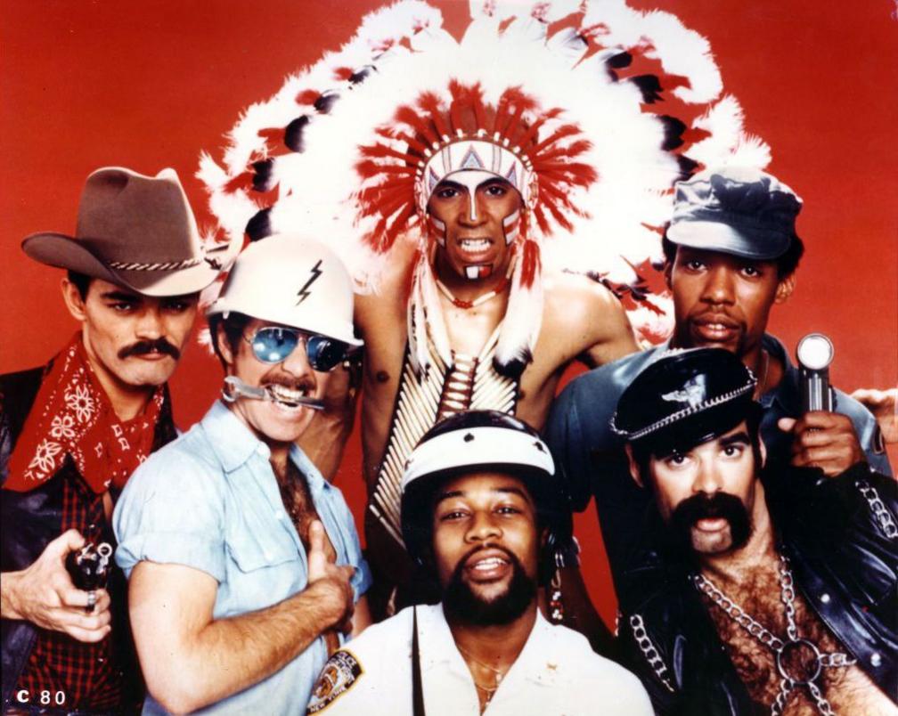 The Village People pose in a group studio shot wearing their various costumes against a red background, taken in 1977.