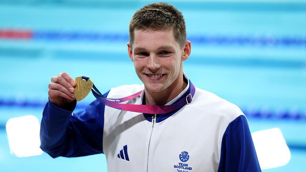 Duncan Scott holds up his gold medal from the men's 200m individual medley on day one