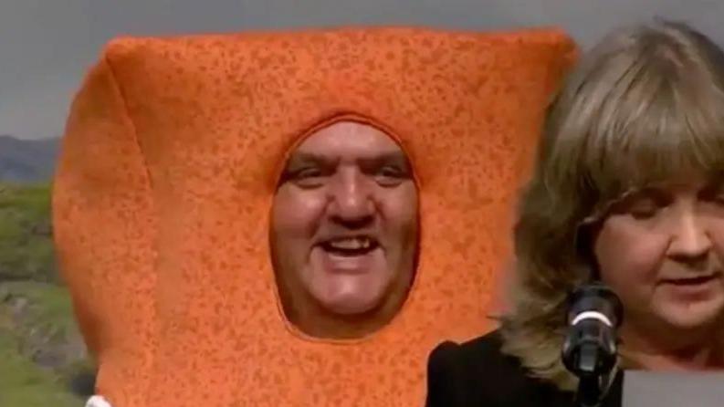 Paul Ellis's smiling face pokes through a fishfinger costume, as the returning officer in the foreground delivers the result.