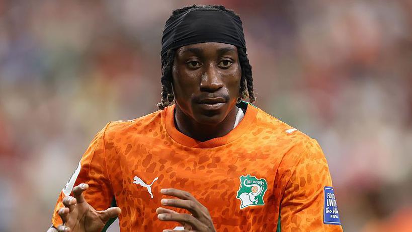 Yan Diomande in black headband and bright orange Ivory Coast kit