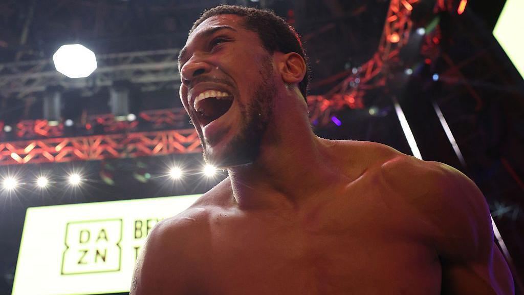 Close-up view of a bare-chested Anthony Joshua celebrating with his mouth wide open, looking happy, after his win in Jeddah