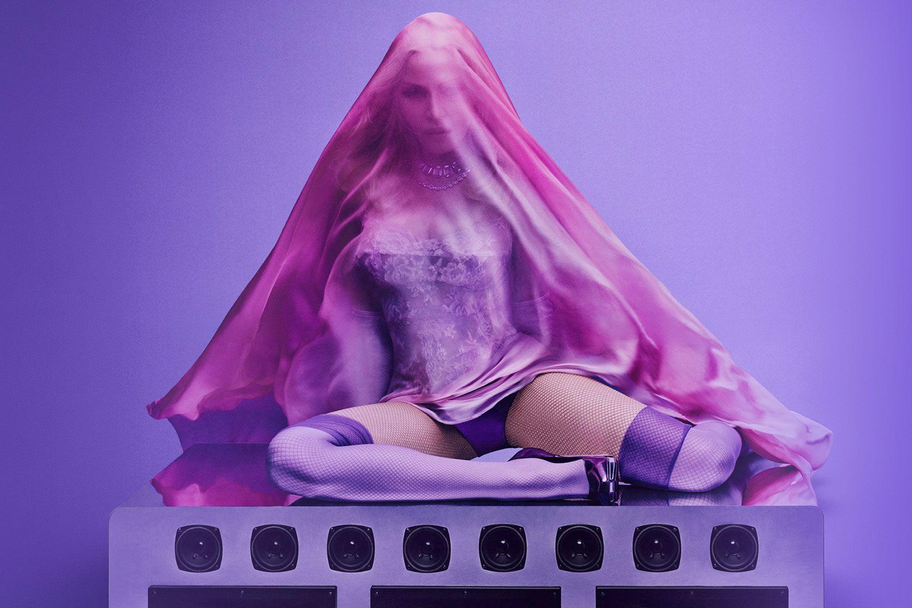 Madonna sits on top of an array of speakers, covered in a pink/purple veil, as part of the cover art for her fifteenth album, Confessions II.