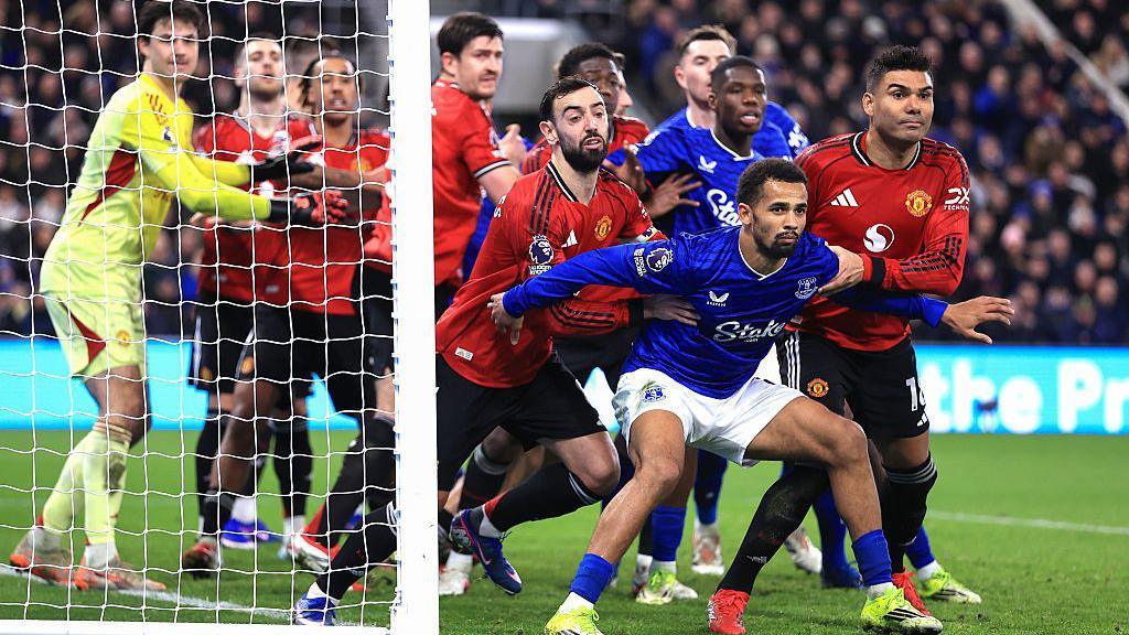 Iliman Ndiaye of Everton holds back Bruno Fernandes and Casemiro of Manchester United as players jostle at a corner kick