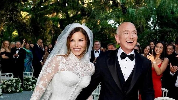 Lauren Sánchez wears a Dolce & Gabbana haute couture gown while Jeff Bezos places his arm around her while wearing a smart black tuxedo