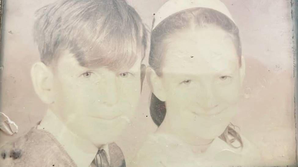 A black and white image of a young girl and boy