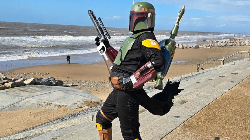 A trooper from one of the Star Wars franchise shows with a full helmet, gun and rocket launcher stands on Cleveleys beach.