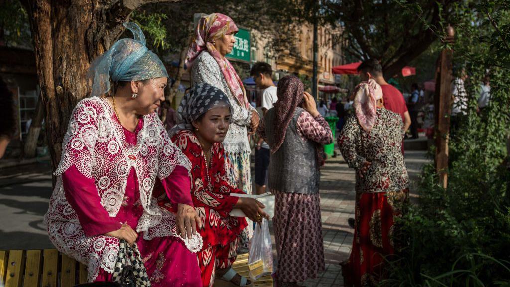 Uyghur women wearing traditional clothes seen watching the Uyghur dancing show in the streets of Kashgar, northwestern Xinjiang.