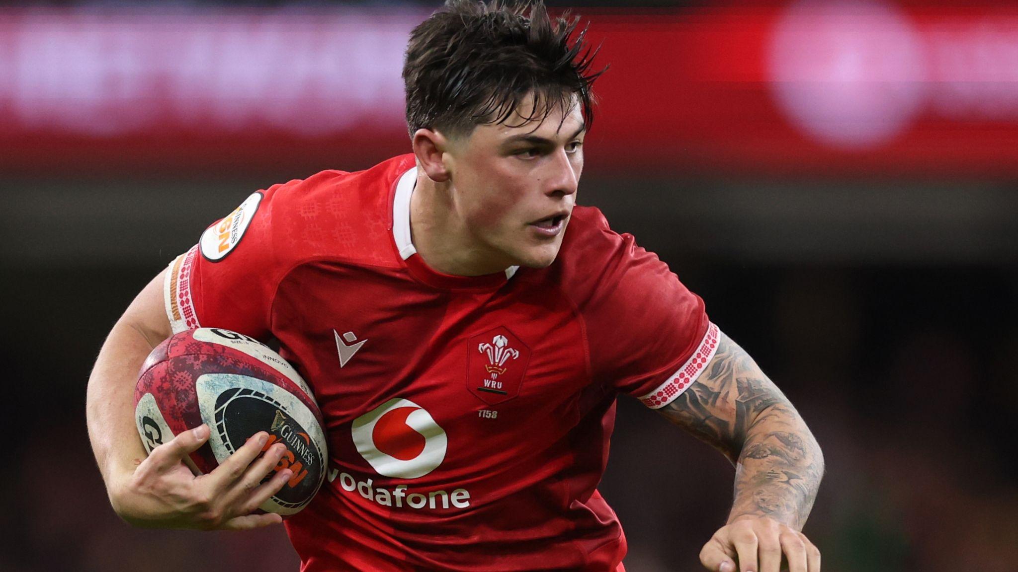 Louis Rees-Zammit playing in the red of Wales with ball under right arm