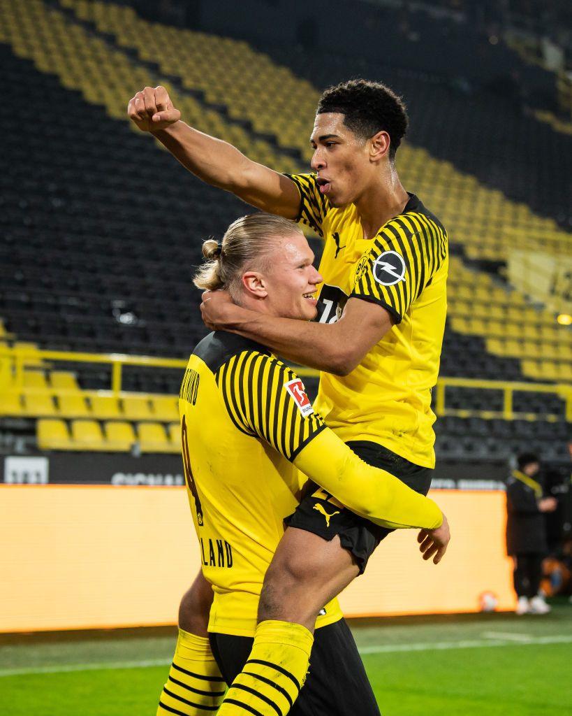 Bellingham is pictured having jumped into Haaland's arms during a match. The pair are both dressed in a yellow football kit.