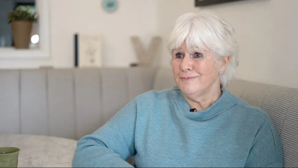 Ann Keen sitting at a kitchen table in a grey jumper