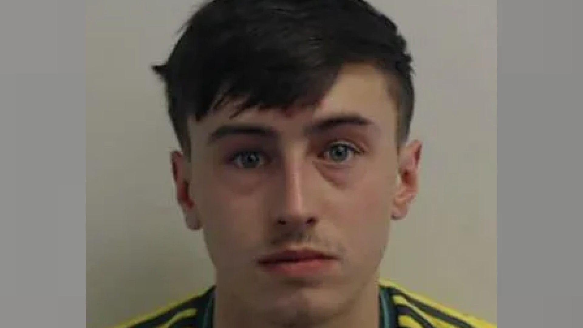 a mugshot of a young man with short brown hair wearing a gold and green football top