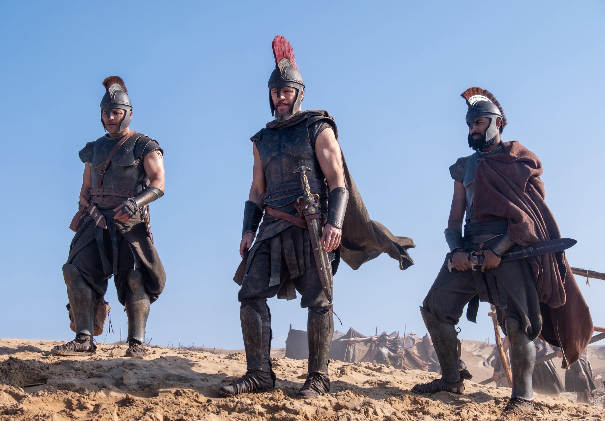 (L-R) Jimmy Gonzales as Cepheus, Matt Damon as Odysseus and Himesh Patel as Eurylochus in their warrior outfits, armoury and swords