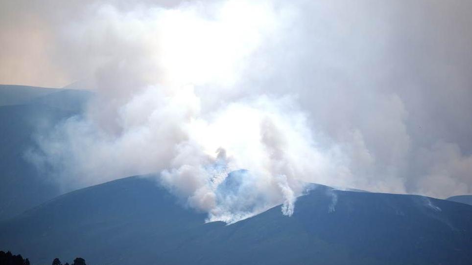 large plumes of white smoke emerge from above a mountain