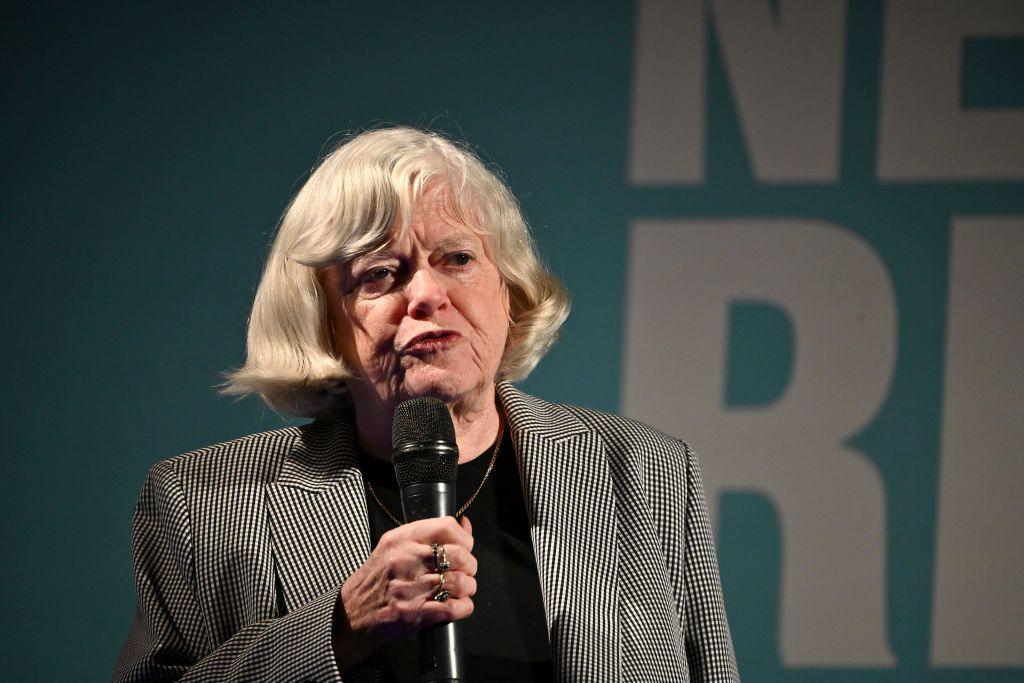 Ann Widdecombe is speaking into a microphone at a Reform UK rally. She wears a blazer and black top.