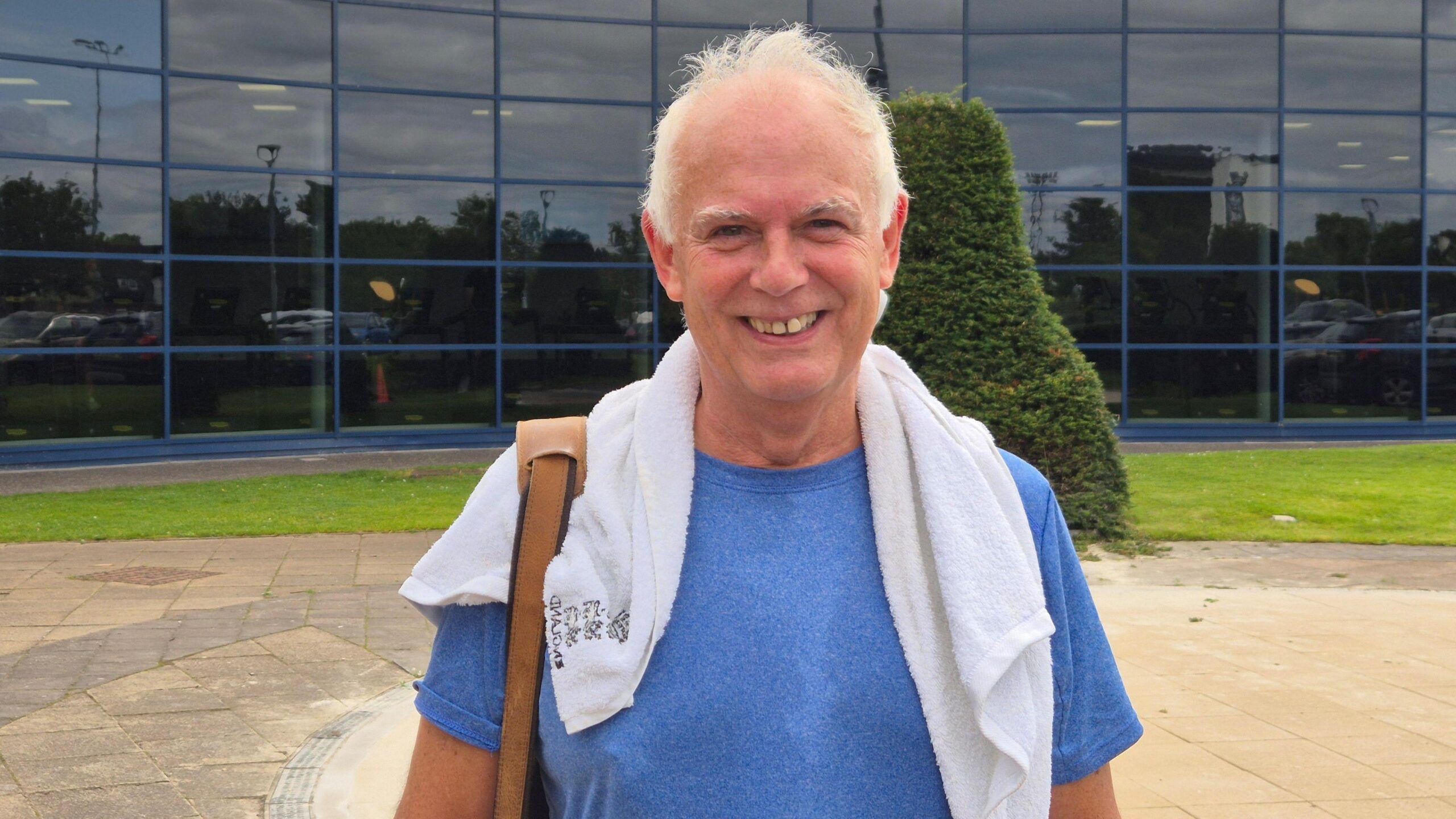 Steven Foster, a man with a blue T-shirt and towel, standing outside a gym