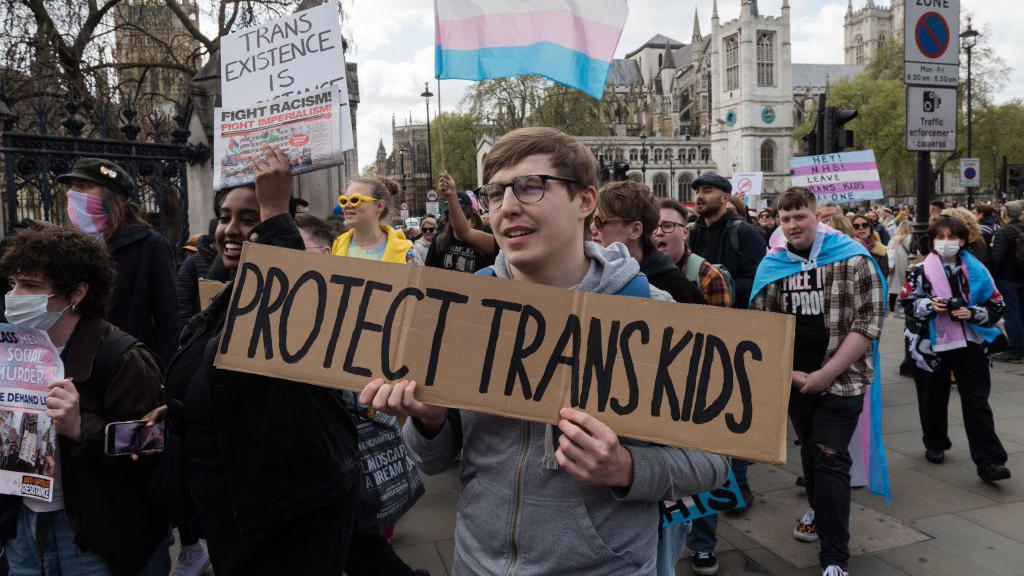 Demonstrators pictured in central London in April 2024 protesting against the ban on puberty blockers. A sign held by a demonstrator in the middle of the shot reads "protect trans kids".