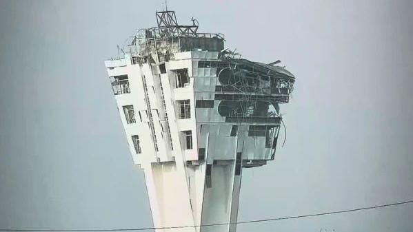 A large control tower is shown with windows blown out and the exterior crumbling
