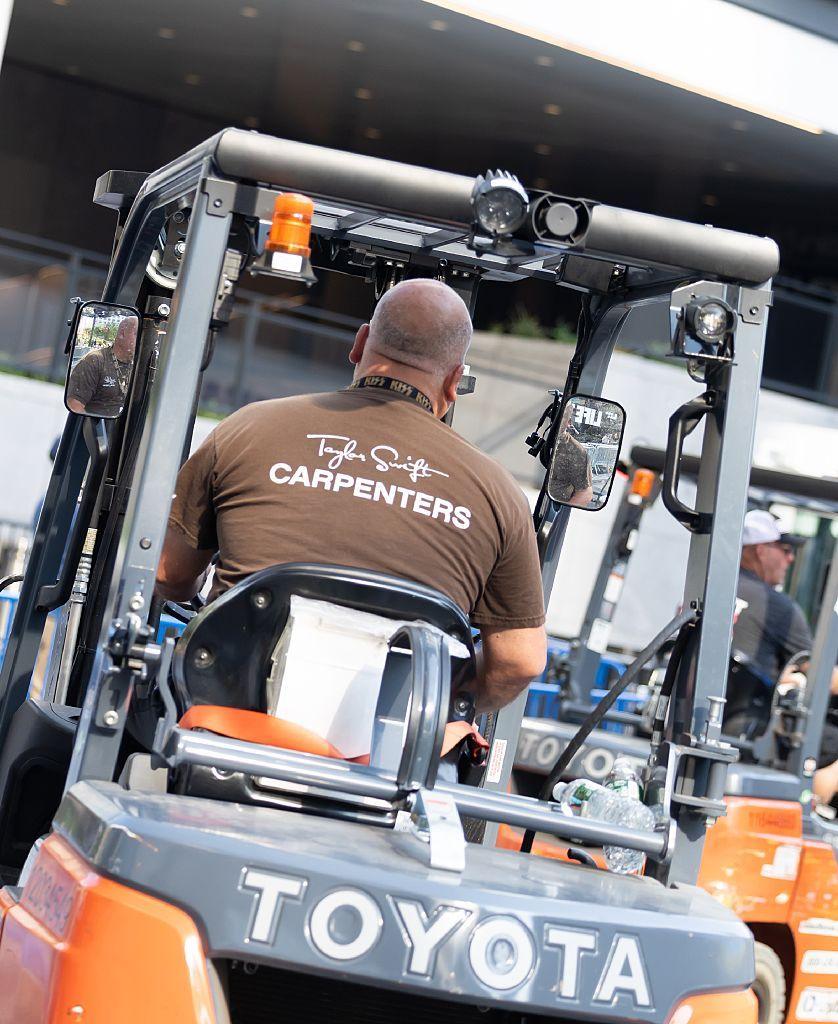 A worker with a Taylor Swift T-shirt is seen on a forklift outside the arena