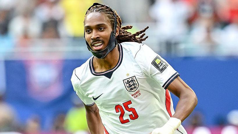 Djed Spence in World Cup action for England, wearing a large black chin brace and England's largely white kit