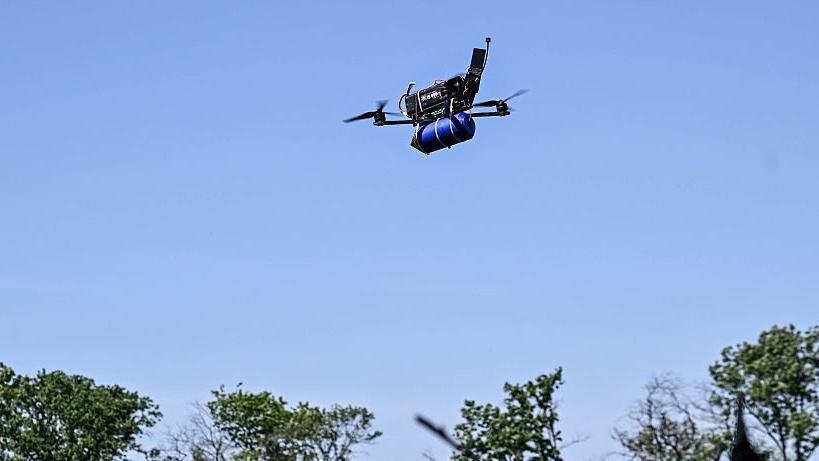 A remotely controlled FPV drone, equipped with ammunition, is seen in the sky during a combat mission of a Ukrainian drone unit in 2025