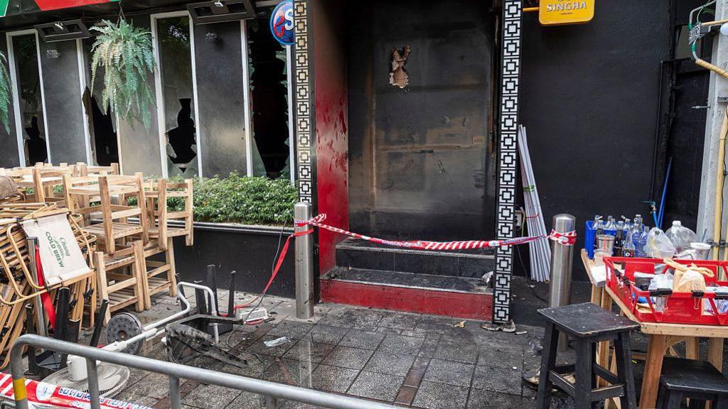 Scorched debris and charred remnants litter the exterior grounds of the Lat Phrao entertainment venue