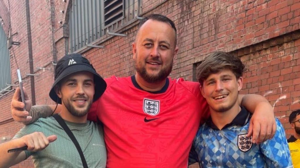 Sean Carrington (centre) with friends Dwain Leonard and Rhys Cheetham wearing England shirts. They are Manchester's Depot Mayfield fanzone before the England v Argentina World Cup semi-final match was screened