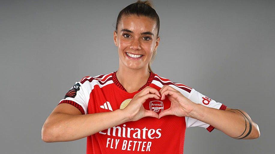 Selina Cerci makes a heart symbol over the Arsenal badge