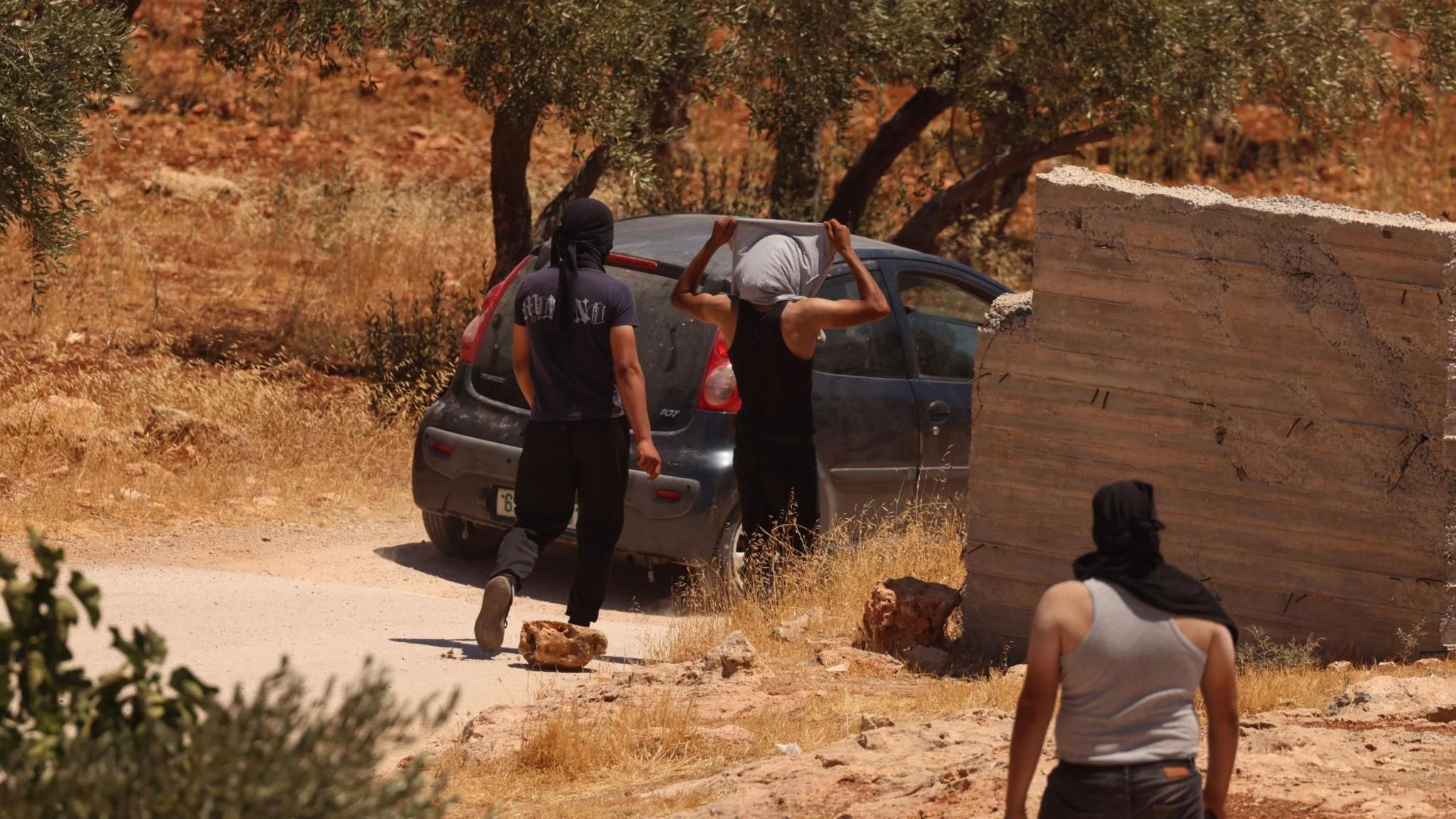 Palestinian men with their heads covered clash with Israeli forces in the village of al-Mughayyir, near Ramallah, in the Israeli-occupied West Bank (11 July 2026)