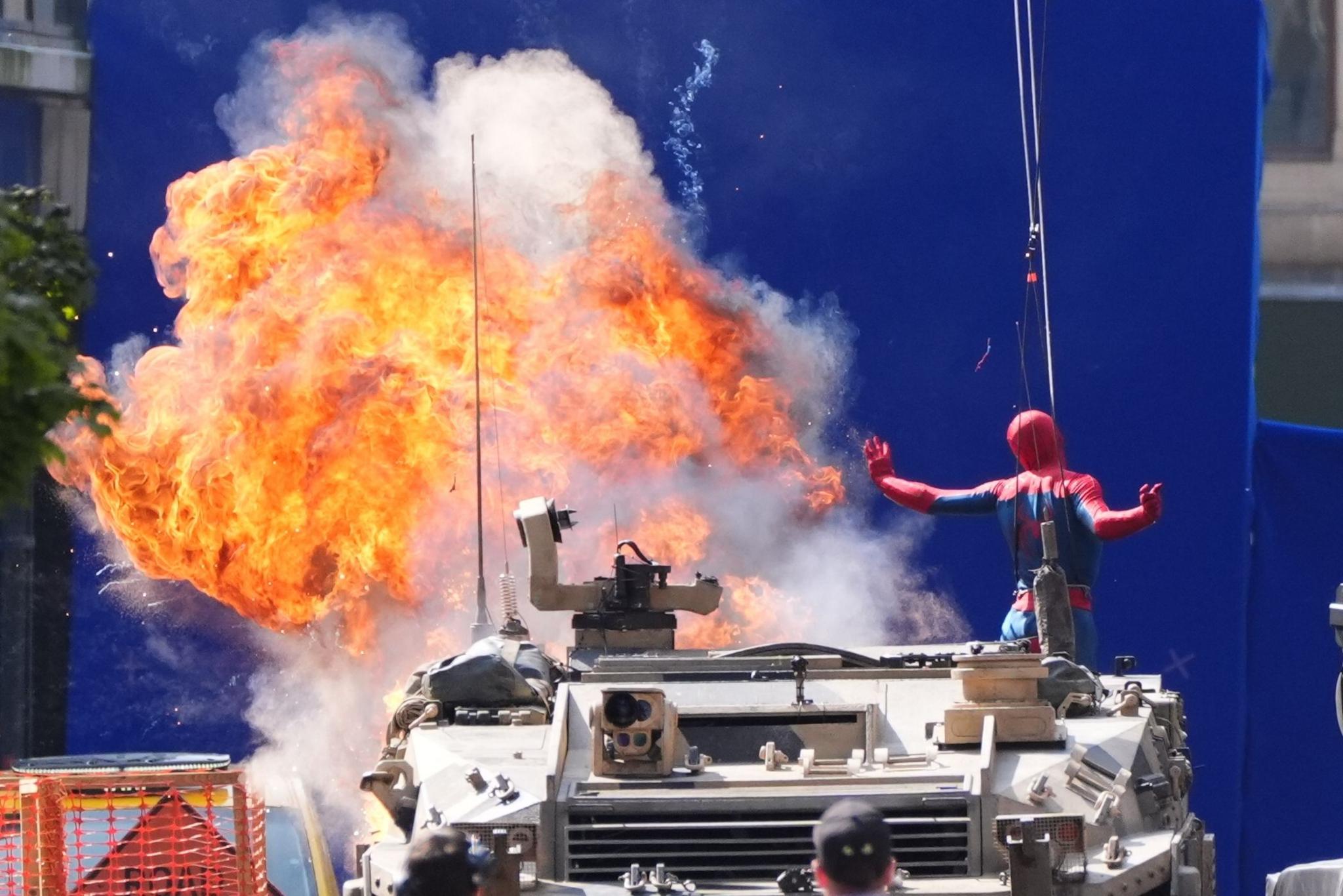 Spiderman looks to be jumping off a tank as an explosion happens behind him