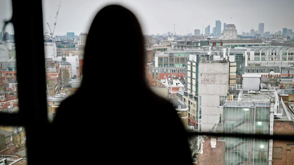Silhouette of a woman looking over the London skyline