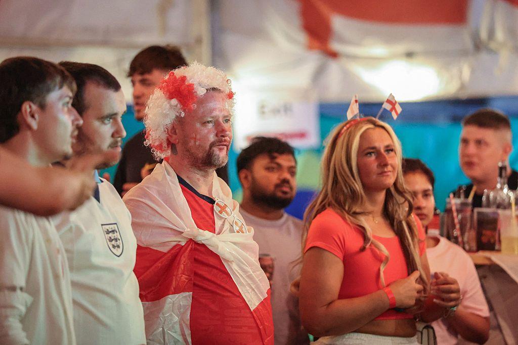 England supporters watch the television broadcast of the 2026 World Cup at a pub in Hebburn, north-east England, with Enland flags draped behind them and wearing England costumes.