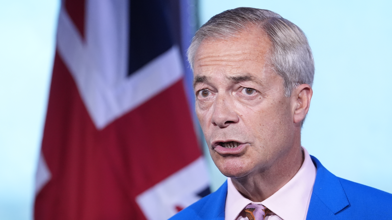 Reform UK leader Nigel Farage makes a statement with a union jack in the background