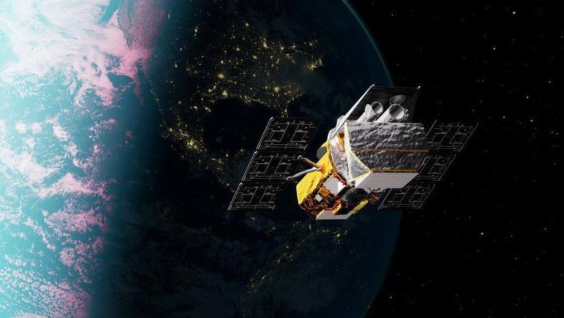A gold‑coloured space telescope with solar panels and a cylindrical black opening floats in space above the Earth.