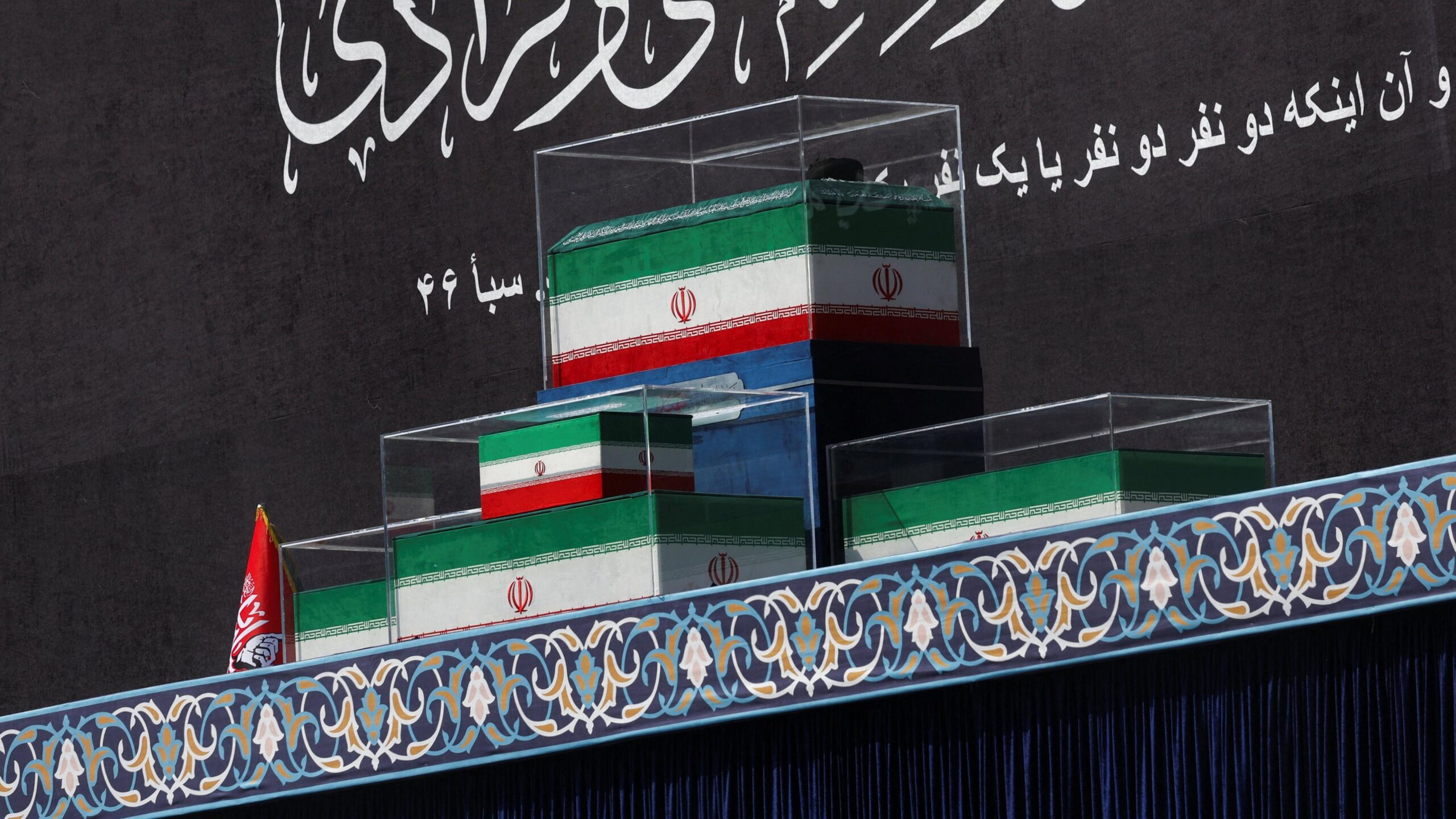 The coffins of Iran's late Supreme Leader Ayatollah Ali Khamenei and his family members in the colours of Iranian flags sit on stage at the Grand Mosalla in Tehran.