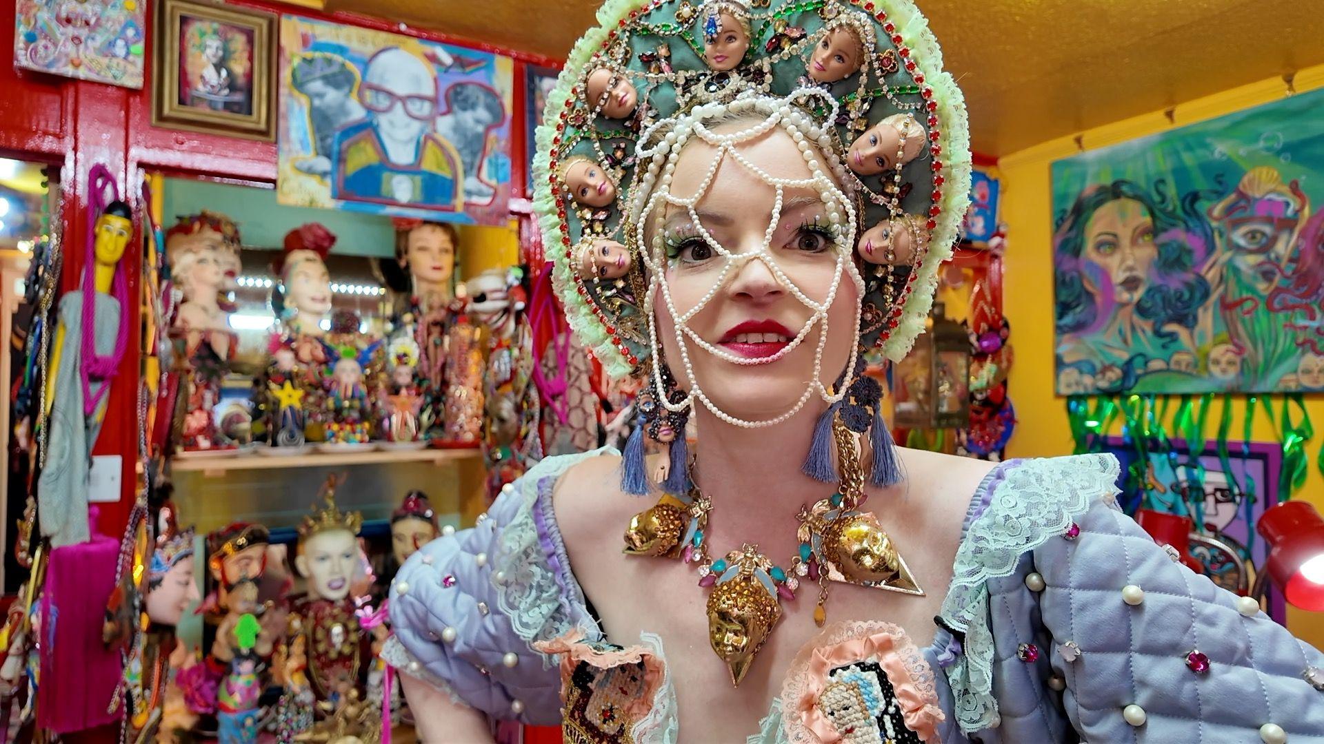 A young woman wearing an elaborate headdress and beaded face mask