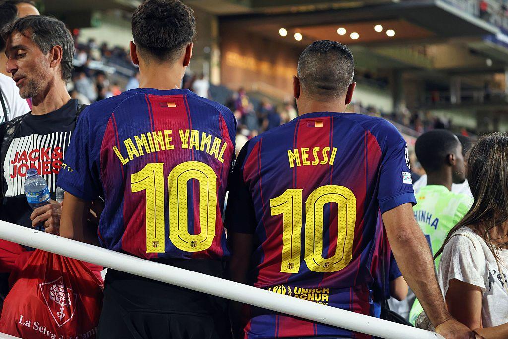 Two Barcelona fans wear football shirts with number ten on the back, the left bearing the name of Lamine Yamal and the right the name of Lionel Messi