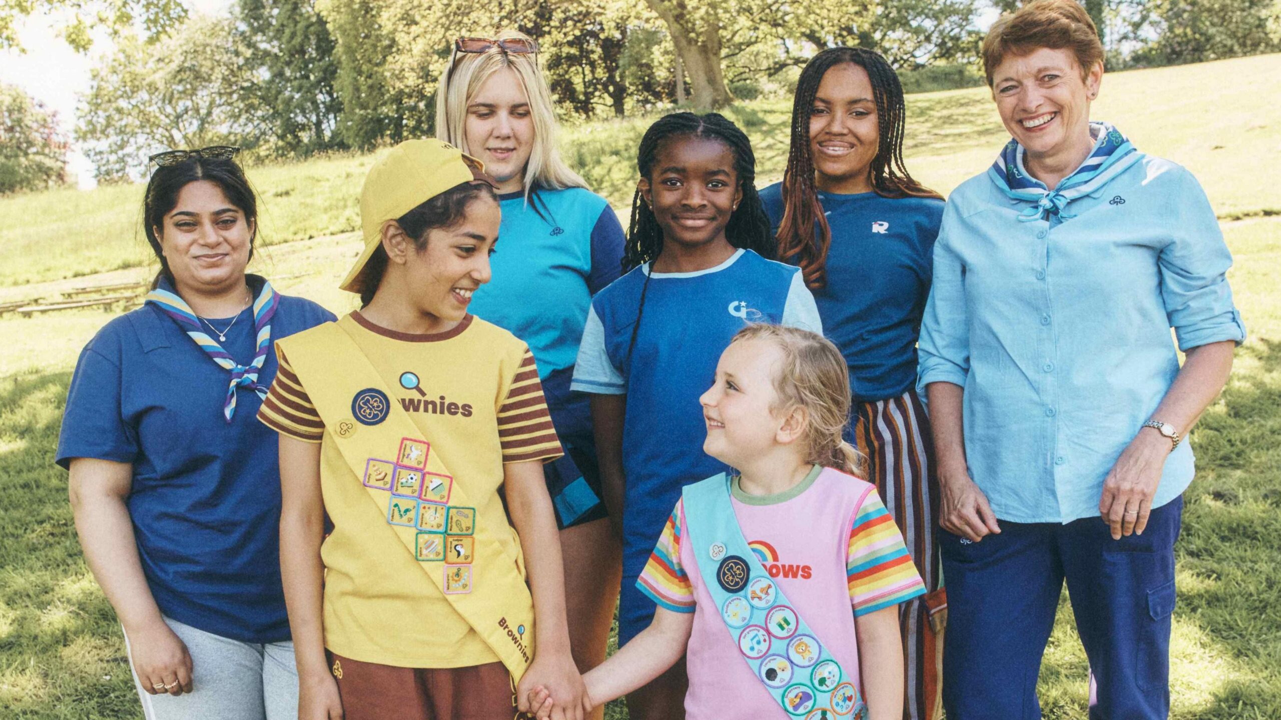 A mixture of girls, young women and an older woman, all wearing different Girlguiding uniforms.