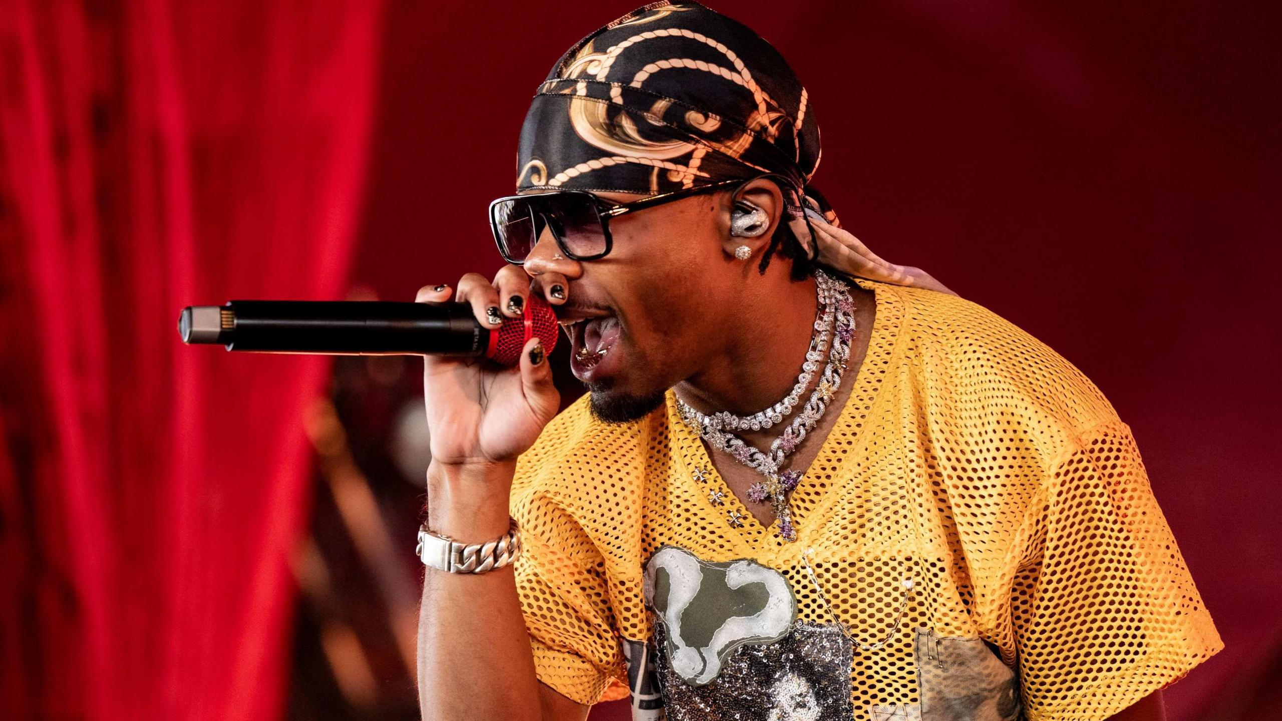D4vd at Coachella last year, wearing a yellow mesh T-shirt and singing into a microphone