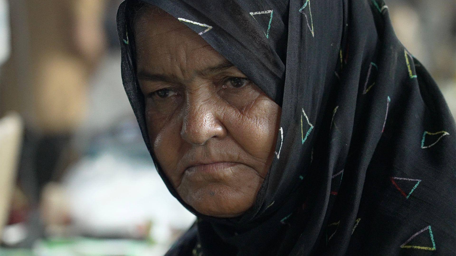 Headshot of a woman wearing a black headscarf decorated with multi-coloured triangles.