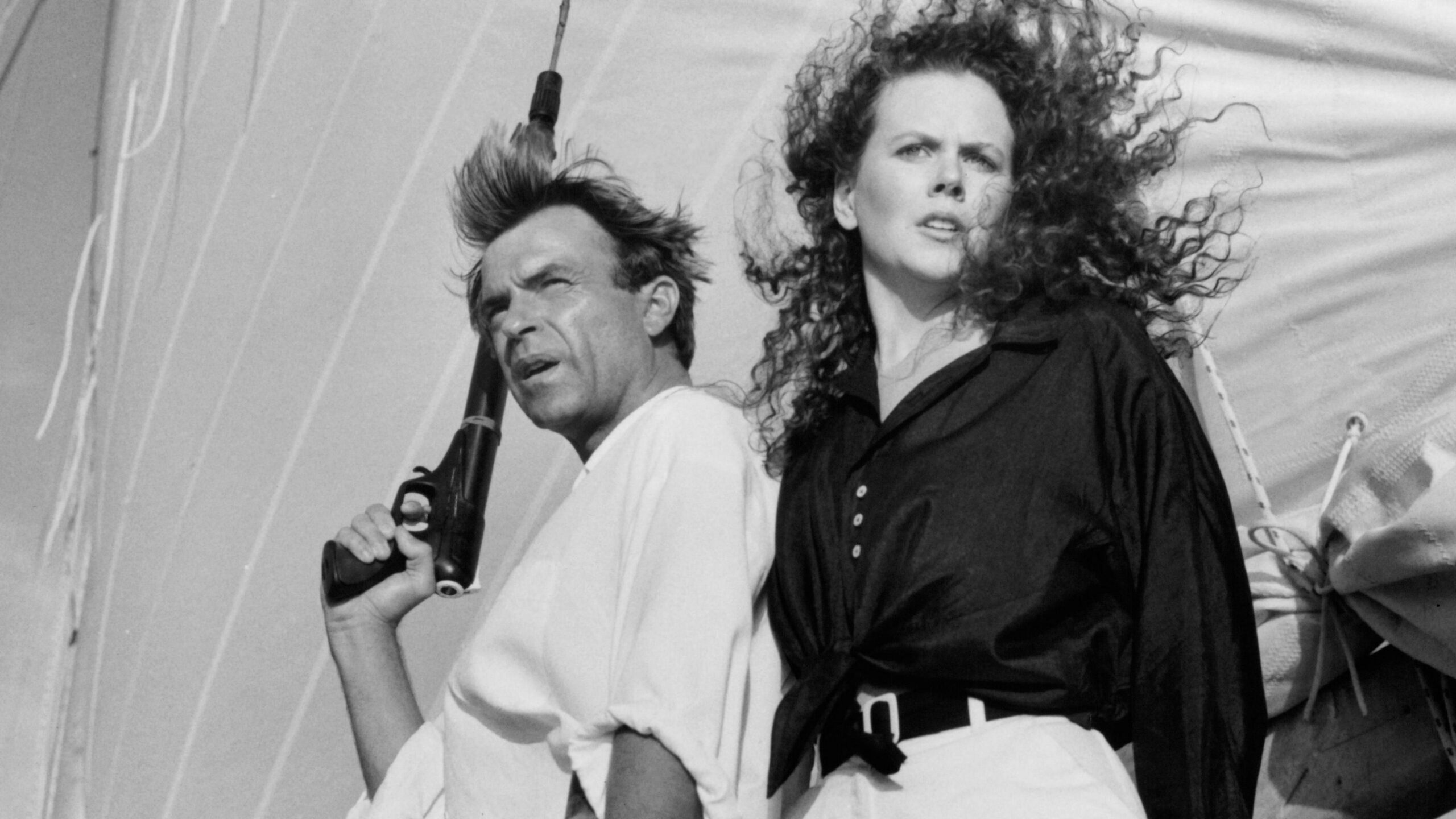Actor Sam Neill and Actress Nicole Kidman on the set of the Warner Bros movie "Dead Calm" circa 1989. He is holding a gun