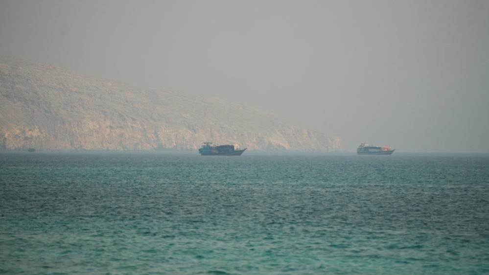 Two vessels are seen in the Strait of Hormuz, surrounded by rocky mountains, from Musandam, Oman