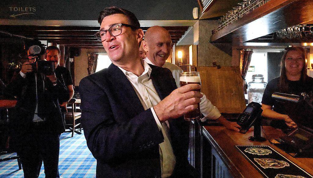 Andy Burnham holds a pint inside a pub