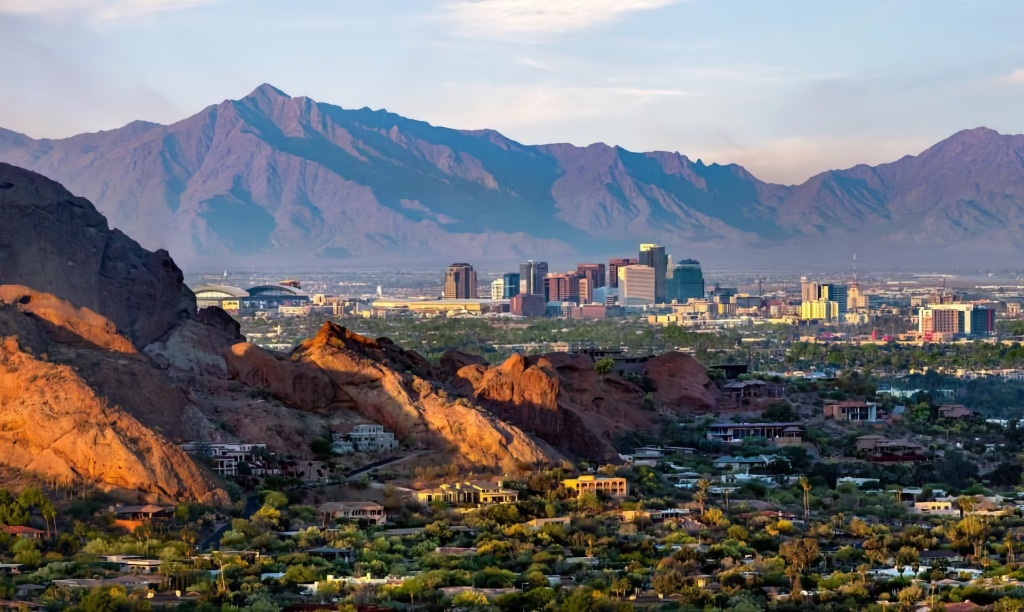 The downtown Phoenix, Arizona skyline at dusk with Camelback Mountain and desert rock formations in the foreground, host city of WordCamp US 2026