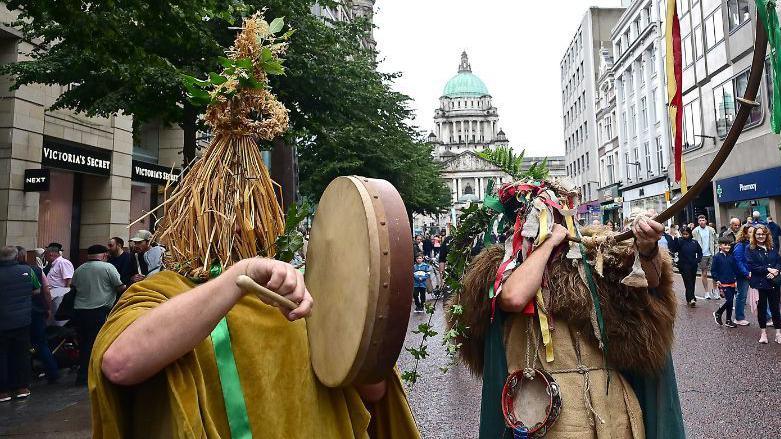 People in mumming outfits with Belfast city hall in background