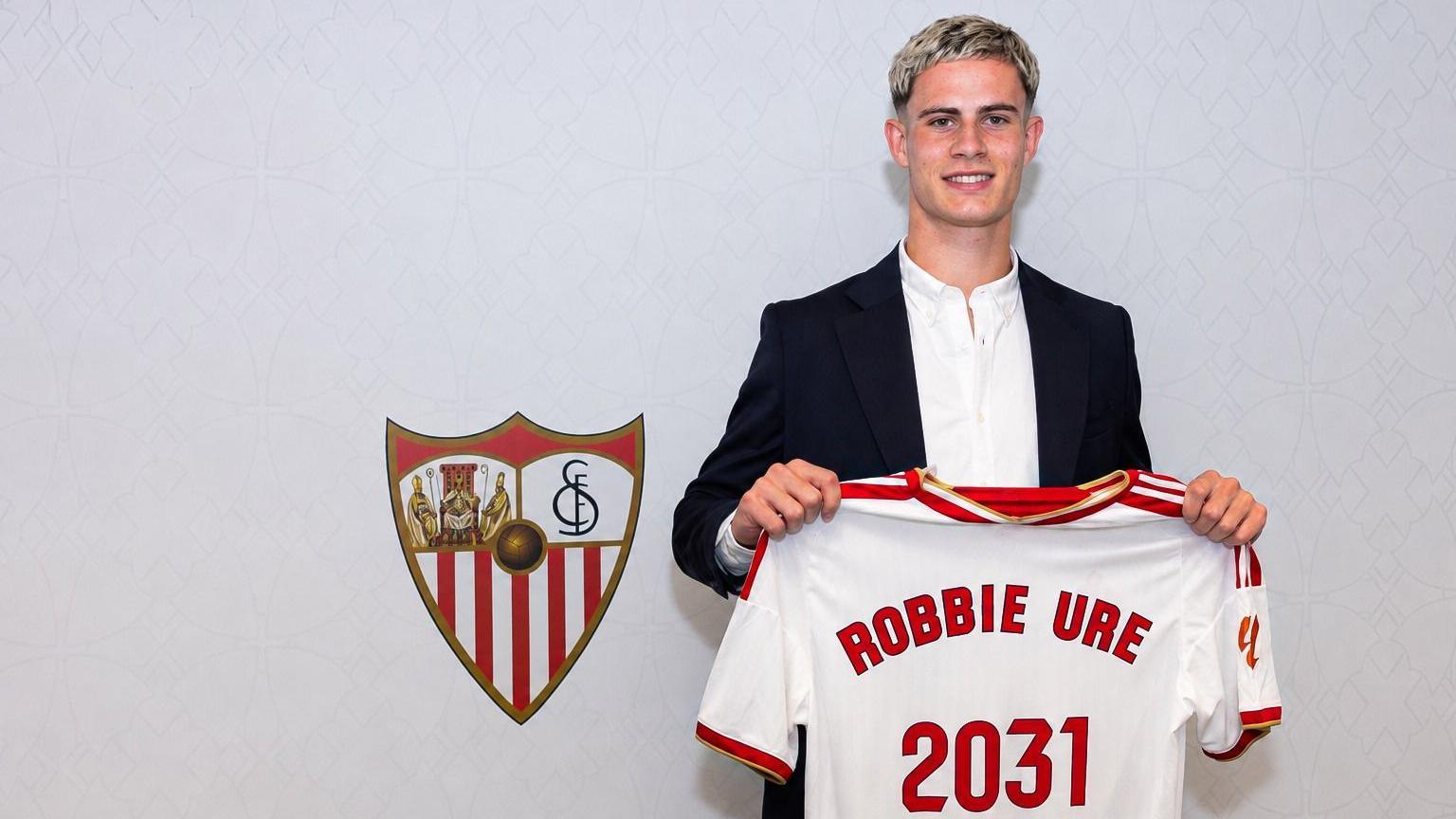 Robbie Ure holding the Sevilla shirt in front of the badge