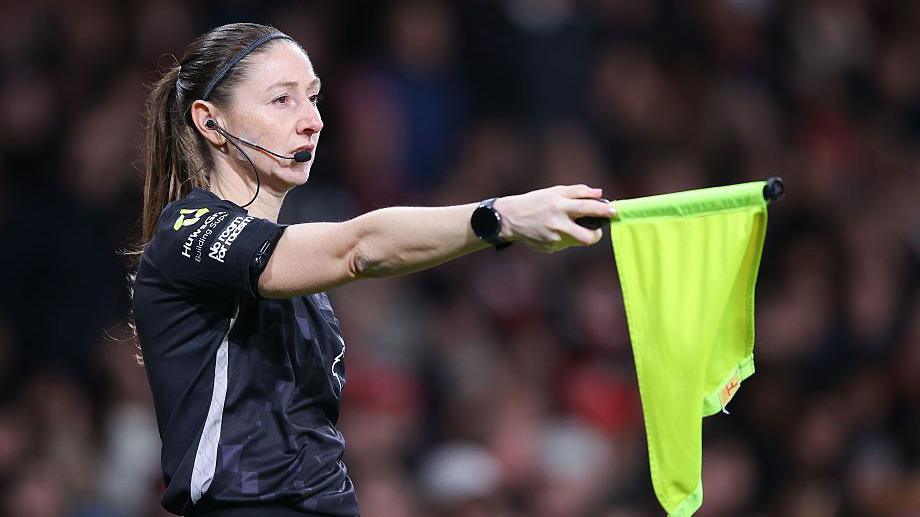 Sian Massey-Ellis holding a flag during a Premier League match
