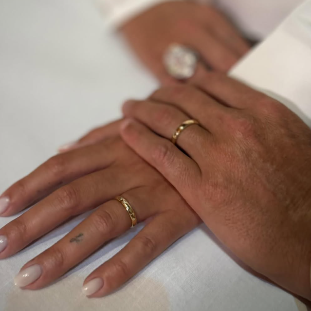 Wedding rings seen in the hands of two people, one on top of the other