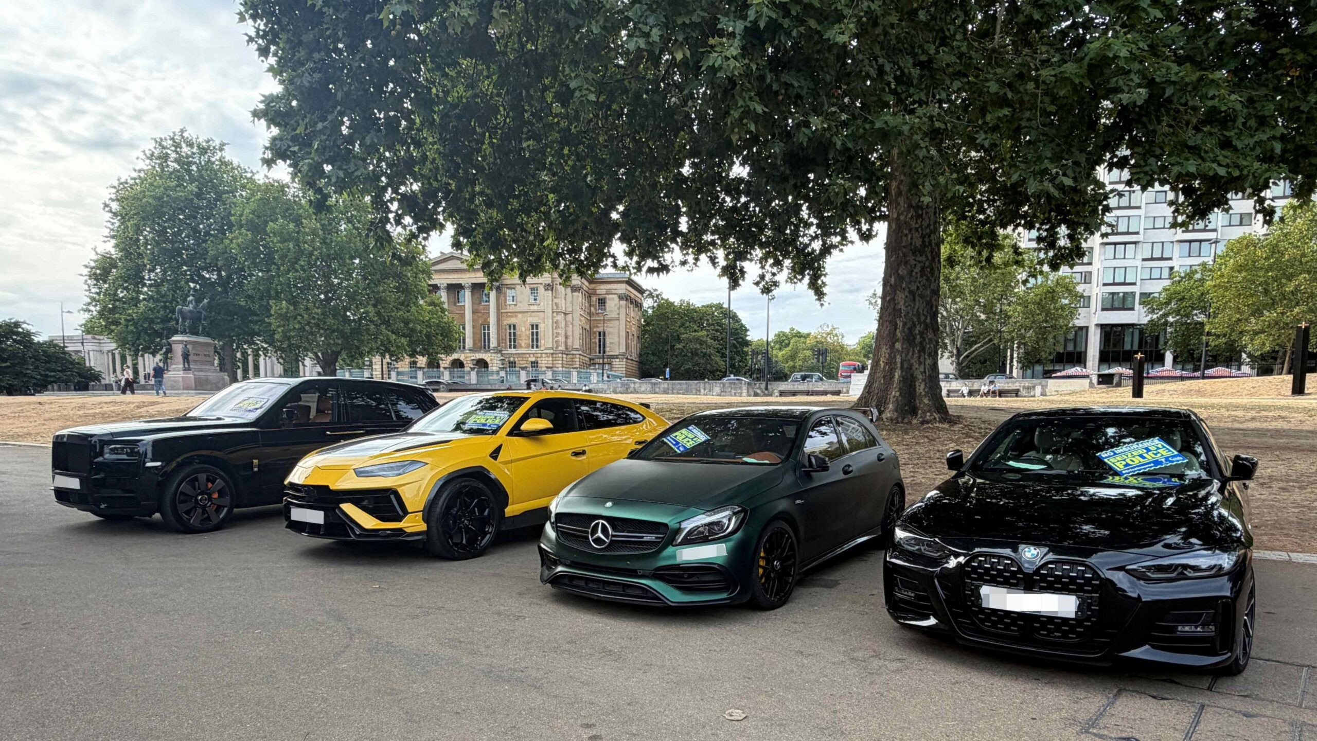 A Black Rolls-Royce, yellow Lamborghini, green Mercedes and black BMW parked side by side after being seized