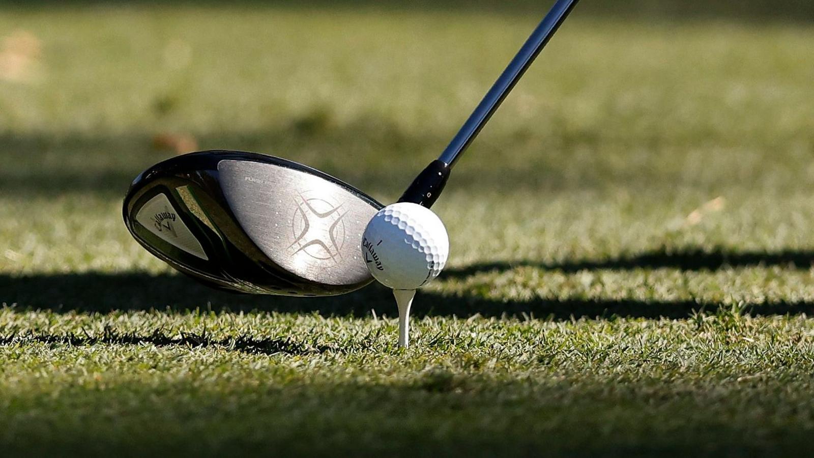 An image of a golf club and golf ball on a tee