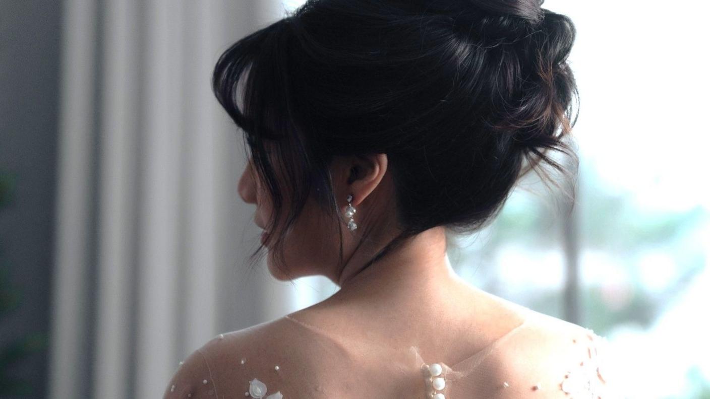 A bride with her in an updo looks over her shoulder.